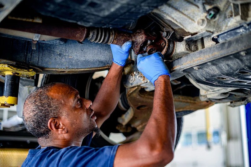 Mechanic repairing car driveshaft assembly